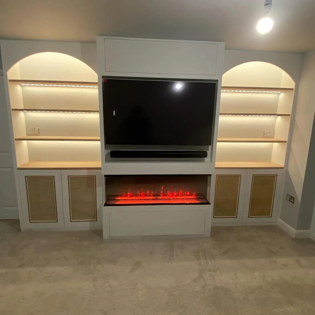 Built-in media wall with warm LED strip lighting under oak shelves and an electric fire
